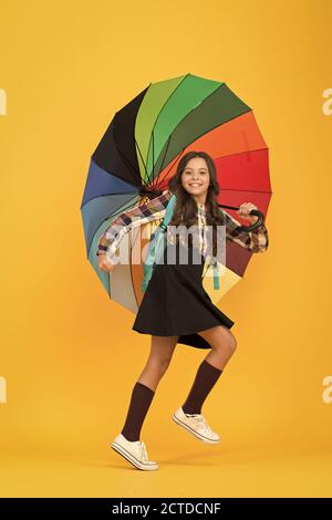 Sentiment sec... les couleurs arc-en-ciel pressé jusqu'à l'école. bonne météo. sous mon parapluie. petite fille parapluie. style automne lumineux. rester positif toute saison. Heureux l'enfant protégé de la pluie. Banque D'Images