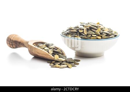 Graines de citrouille pelées dans une cuillère en bois isolée sur fond blanc. Banque D'Images