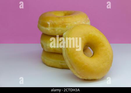 Quatre Donuts ou classiques Donuts empiler avec sur un blanc Et arrière-plan rose Banque D'Images