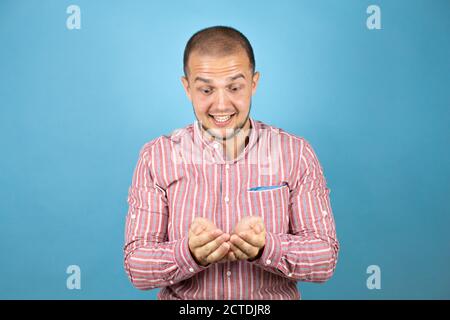 Homme d'affaires russe sur fond bleu souriant avec les mains paumes ensemble recevoir ou donner le geste. Maintien et protection Banque D'Images