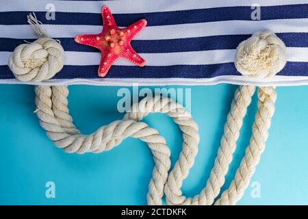 Coquillages, étoiles de mer et textile sac marine à nœuds de corde sur fond bleu clair. Vacances d'été et concept de vacances Banque D'Images