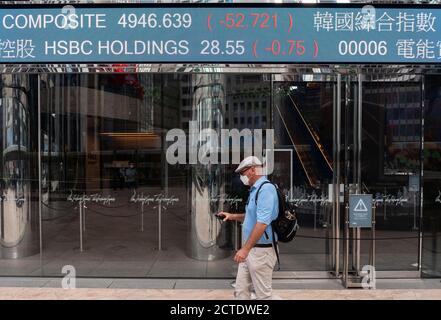 Un piéton passe devant un tableau d'affichage du marché boursier montrant les résultats négatifs de HSBC à Hong Kong. Banque D'Images