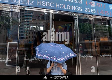 Un piéton passe devant un tableau d'affichage du marché boursier montrant les résultats négatifs de HSBC à Hong Kong. Banque D'Images