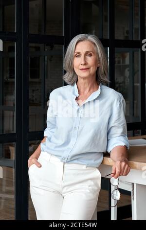 Femme d'âge moyen, mûre et confiante, debout sur le lieu de travail du bureau, portrait. Banque D'Images