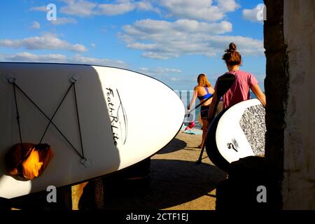 Les amateurs de plage de l'île de Wight de Freshwater Bay transportent des planches à ramer La promenade du front de mer jour d'été beau temps août vacances de banque week-end Banque D'Images