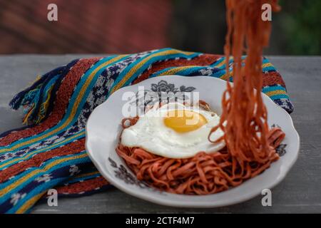 Les nouilles instantanées frites sont appréciées avec des œufs frits sur un Assiette avec un ornement en tissu typiquement indonésien Banque D'Images