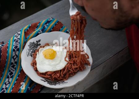 Les nouilles instantanées frites sont appréciées avec des œufs frits sur un Assiette avec un ornement en tissu typiquement indonésien Banque D'Images