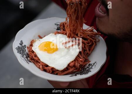 Les nouilles instantanées frites sont appréciées avec des œufs frits sur un Assiette avec un ornement en tissu typiquement indonésien Banque D'Images