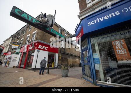 La face changeante de la rue haute. Un homme portant un masque facial de protection se tient à l'extérieur des boutiques, dont beaucoup sont fermées, dans une rue calme et élevée de Catford, dans le sud de Londres, environ six mois après la soirée du 23 mars, lorsque le Premier ministre Boris Johnson a annoncé des restrictions à l'échelle nationale. Banque D'Images
