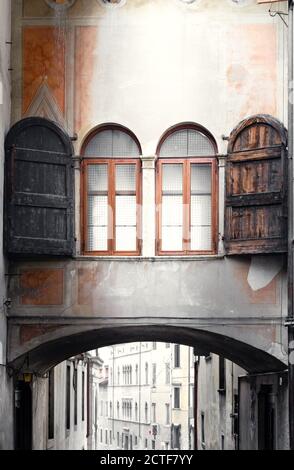 Vue sur le bâtiment historique du centre. Structure à fenêtre qui relie deux bâtiments. Murs décorés de fresques usées. Feltre, Belluno, Italie Banque D'Images