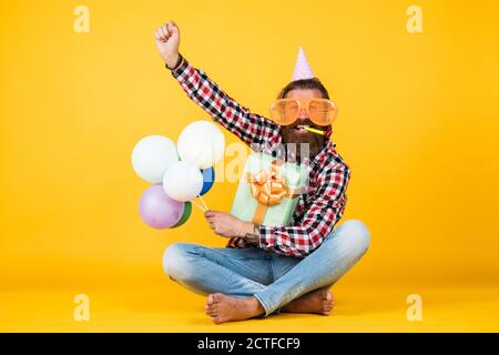 Event Manager pose avec un accessoire festif. Concept amusant et heureux. Homme heureux tenant des ballons d'hélium colorés. hipster souriant heureux. S'amuser en fête. Préparez-vous pour les vacances. Gestionnaire d'événements. Banque D'Images