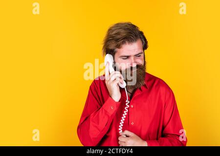 vous êtes triste dans la conversation. un boxeur mûr avec une barbe et un téléphone rétro. un homme brutal de race blanche parle au téléphone. concept de communication. un barbu répond à l'appel. un homme beau a une conversation. Banque D'Images