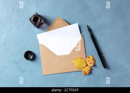 Maquette de papeterie d'automne, carte de vœux A5 vierge ou invitation dans une enveloppe kraft brune, plan de pose à plat avec un stylo à encre et un puits d'encre Banque D'Images