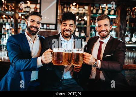 De vieux amis joyeux qui s'amusent et boivent de la bière au bar du pub. Banque D'Images