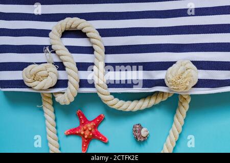 Coquillages, étoiles de mer et textile sac marine à nœuds de corde sur fond bleu clair. Vacances d'été et concept de vacances Banque D'Images