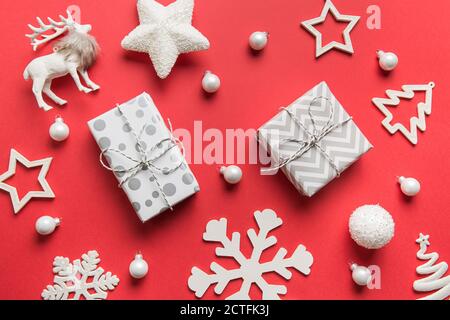 Motif de décorations blanches de Noël, cadeaux, boules, cerfs, flocons de neige sur fond rouge. Vue du dessus, plan d'appartement. Modèle de Noël, maquette pour l'accueil Banque D'Images