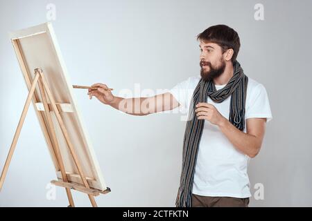 Un artiste d'homme tire sur un chevalet un foulard blanc t-shirt art hobby créativité Banque D'Images