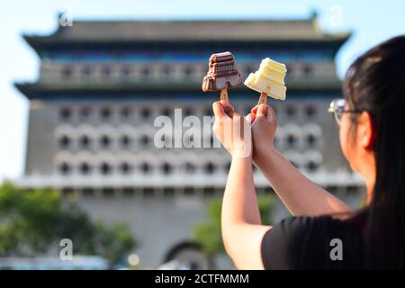 Une personne présente la glace contre la porte de Zhengyang sur la rue Qianmen à Beijing, en Chine, le 11 août 2020. Banque D'Images