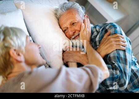 Joyeux couple senior qui s'embrasse, dormant ensemble dans la chambre Banque D'Images