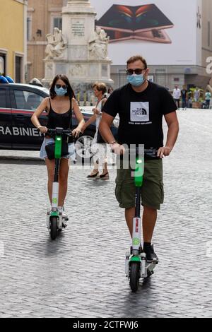 Rome, Italie - 20 septembre 2020 : un couple se déplace dans les rues de la ville en utilisant des scooters électriques à louer. Banque D'Images