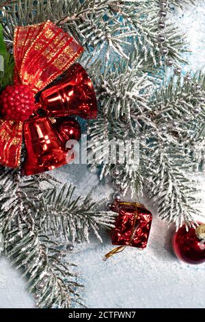 Composition verticale du nouvel an - branches enneigées de l'arbre de Noël. Cloches rouges et cadeaux Banque D'Images