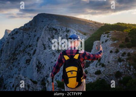 Homme puissant randonneur prenant des photos avec un smartphone au sommet de la montagne. Une merveilleuse pause. Le concept d'activité et la disponibilité de la connexion mobile Banque D'Images