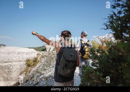 Deux randonneurs avec des sacs à dos et d'autres engins d'escalade restant au sommet du rocher. Homme pointant avec sa main discutant de la route. Plan, vision et mission concep Banque D'Images