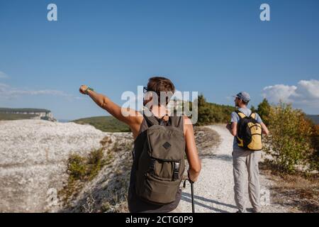 Deux randonneurs avec des sacs à dos et d'autres engins d'escalade restant au sommet du rocher. Homme pointant avec sa main discutant de la route. Plan, vision et mission concep Banque D'Images