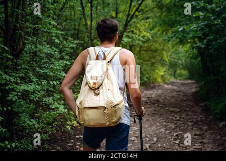 Portrait d'un randonneur marchant sur le sentier dans les bois. Homme de voyage sportif robuste avec sac à dos sur fond de forêt. Banque D'Images