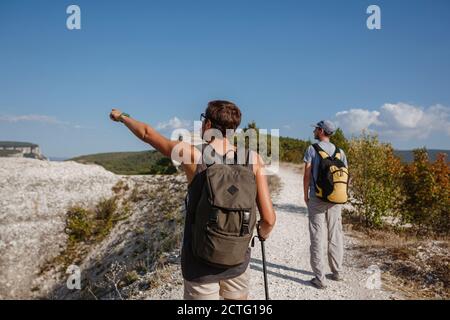 Deux randonneurs avec des sacs à dos et d'autres engins d'escalade restant au sommet du rocher. Homme pointant avec sa main discutant de la route. Plan, vision et mission concep Banque D'Images