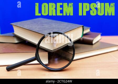 Mise au point sélective loupe quelques livres fermés sur un table en bois marron fond bleu Banque D'Images