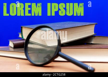 Mise au point sélective loupe quelques livres fermés sur un table en bois marron fond bleu Banque D'Images