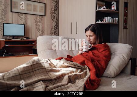 Femme malade et grippe. Pris au froid. Femme se sentant froide avec une couverture reposant sur le canapé à la maison Banque D'Images