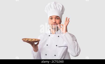 Chef Man Holding Pie gesting Zip votre lèvre, fond blanc Banque D'Images