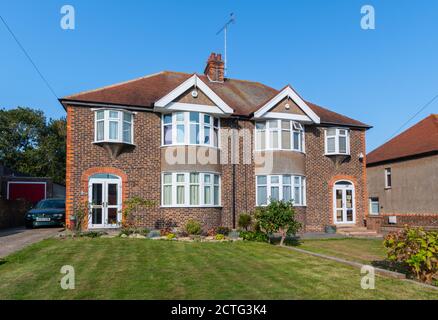 Grandes maisons mitoyennes britanniques des années 1930 de deux étages en briques avec baies vitrées incurvées dans West Sussex, Angleterre, Royaume-Uni. Banque D'Images