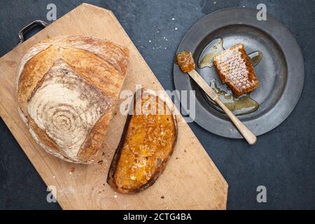 Pain grillé au levain avec nid d'abeille sur une planche à pain. ROYAUME-UNI Banque D'Images