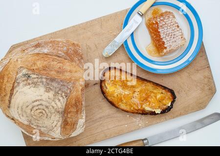 Pain grillé au levain avec nid d'abeille sur une planche à pain. ROYAUME-UNI Banque D'Images