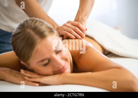 Masseur professionnel faisant un massage thérapeutique. Femme profitant d'un massage dans sa maison. Jeune femme se relaxant massage corporel. Banque D'Images