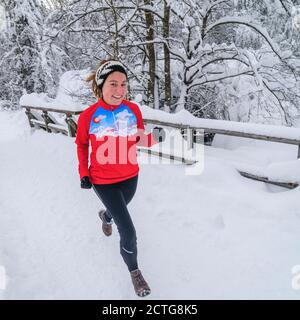 Jeune femme qui fait du jogging dans le parc Wintry Banque D'Images