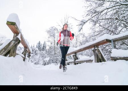 Jeune femme qui fait du jogging dans le parc Wintry Banque D'Images