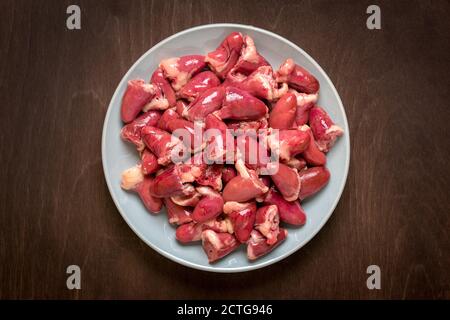 Cœurs de poulet frais crus dans une assiette grise isolée sur du bois Arrière-plan vue du dessus plat Lay Offal prêt pour la cuisine saine nourriture Banque D'Images