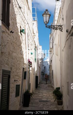 Une figure solitaire sur Vico Clemente Brancasi, une jolie allée dans le vieux centre d'Ostuni, la ville Blanche (la Città Bianca), Apulia, Italie. MODÈLE LIBÉRÉ Banque D'Images