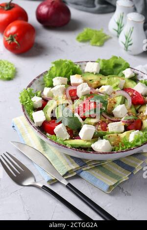 Salade saine avec avocat, tomates, feta et oignon rouge sur fond gris, gros plan Banque D'Images