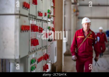 Tableau de commande à distance de l'équipement électrique et du traitement (console). Raffinerie de pétrole et usine de traitement du gaz. Travailleurs de raffinerie flous avec casque blanc. Banque D'Images