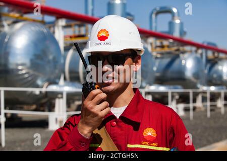 Région d'Aktobe/Kazakhstan - mai 04 : raffinerie de pétrole. Ouvrier de raffinerie asiatique en vêtements de travail rouges et casque blanc avec poste radio. Sur les échangeurs thermiques et Banque D'Images