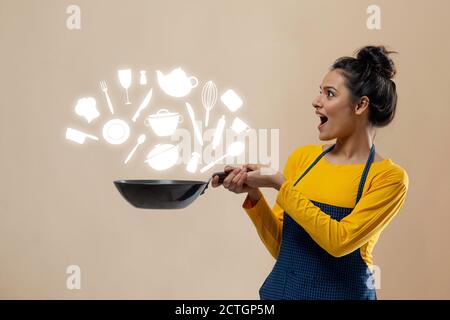 Femme regardant les essentiels de cuisine avec un wok dans elle main Banque D'Images