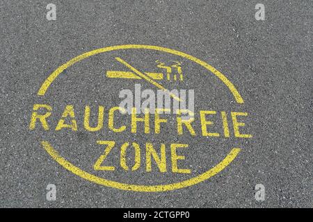 Un panneau rond pour une zone sans fumée sur la rue ou la route asphaltée écrit en allemand avec une photo d'une cigarette écourtée ou annulée. Banque D'Images