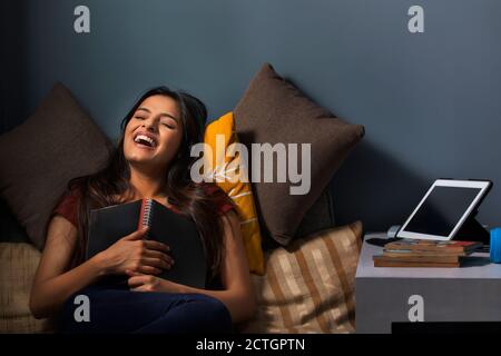 Femme riant après avoir lu une blague d'un journal dans sa main Banque D'Images