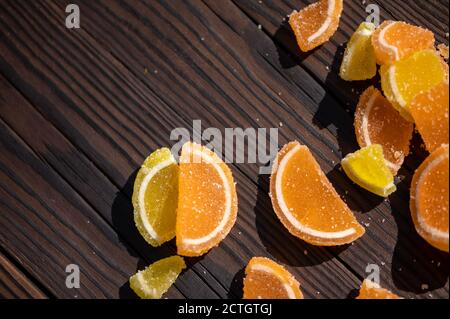 Tranches de citron marmelade éparpillées sur une table en bois au soleil, gros plan, foyer sélectif Banque D'Images