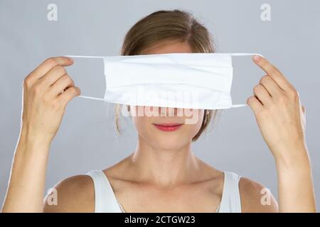 Femme blonde tenant un masque facial couvrant ses yeux devant de sa tête Banque D'Images